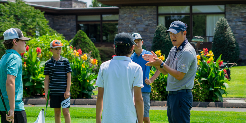 An Op 36 coach teaching a group of junior golfers