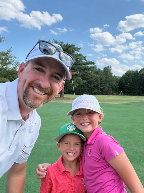A dad and his two kids together on the golf course