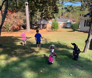 Two junior golfers practicing out in their yard at home